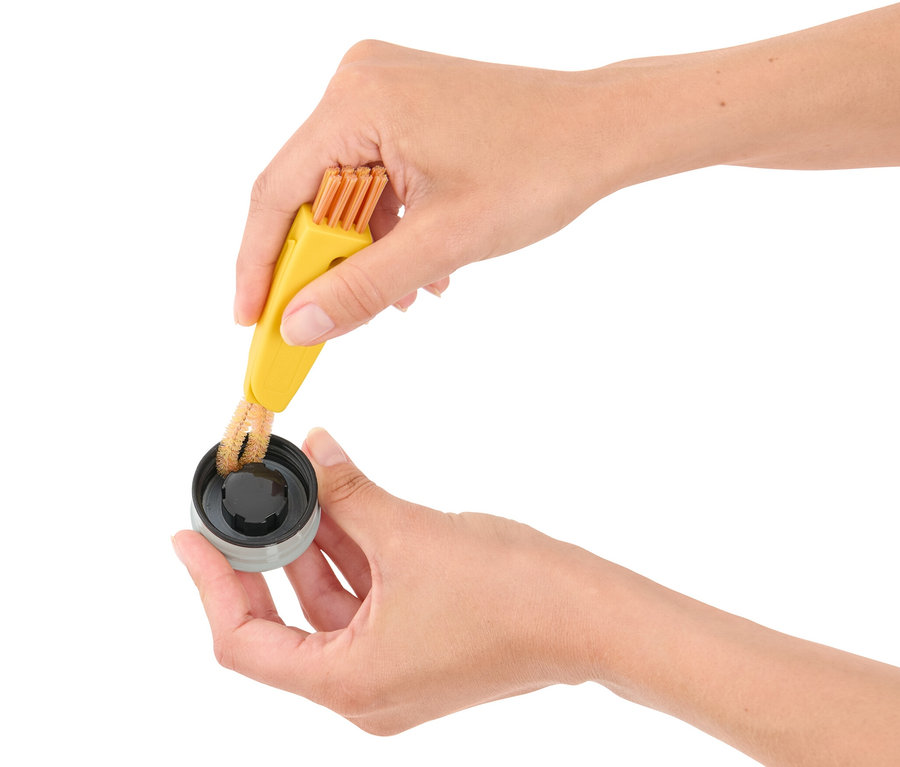 Des mains nettoient un bouchon avec la brosse de nettoyage 3 en 1.