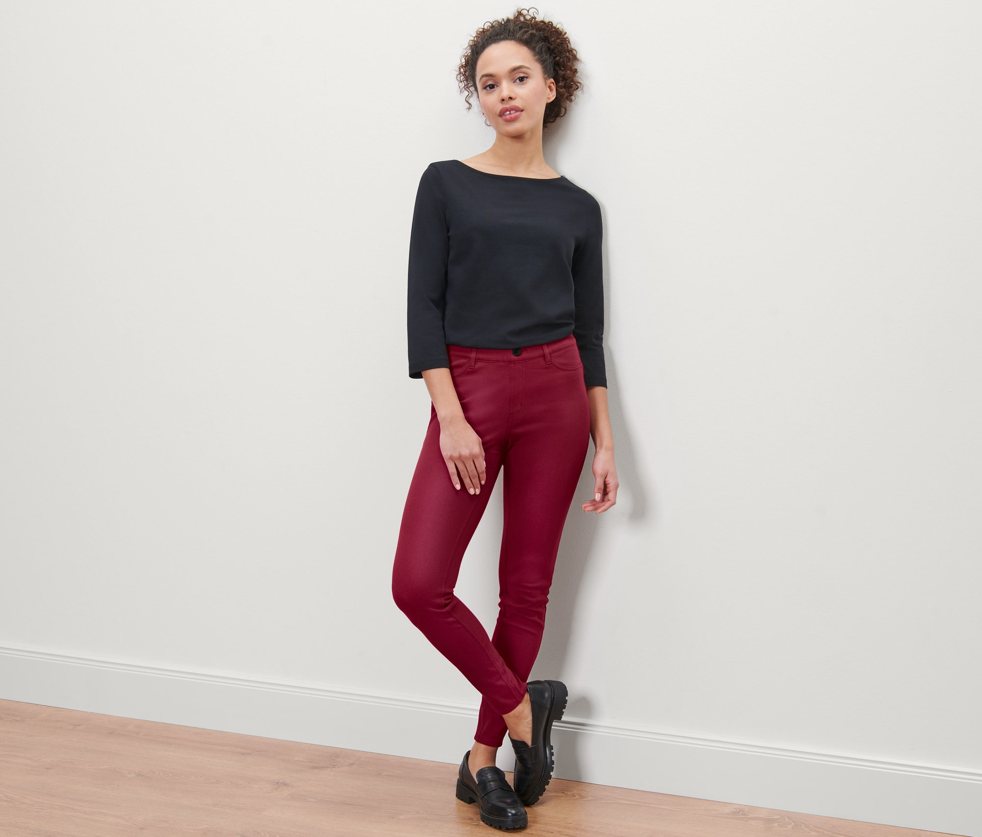 Une femme pose en jegging bordeaux et haut noir.