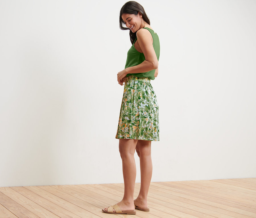 Vue latérale d'une femme portant un haut vert et une robe en jersey imprimée.