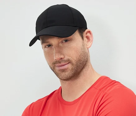 Un homme aux bras croisés portant une casquette de sport noire.