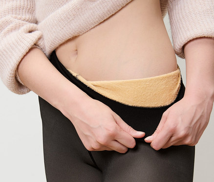 Une femme enfile des collants fins doublés en aspect transparent.