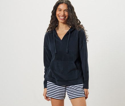 Femme portant un sweatshirt à capuche en tissu éponge et un short rayé.