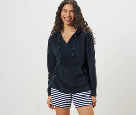 Femme portant un sweatshirt à capuche en tissu éponge et un short rayé.
