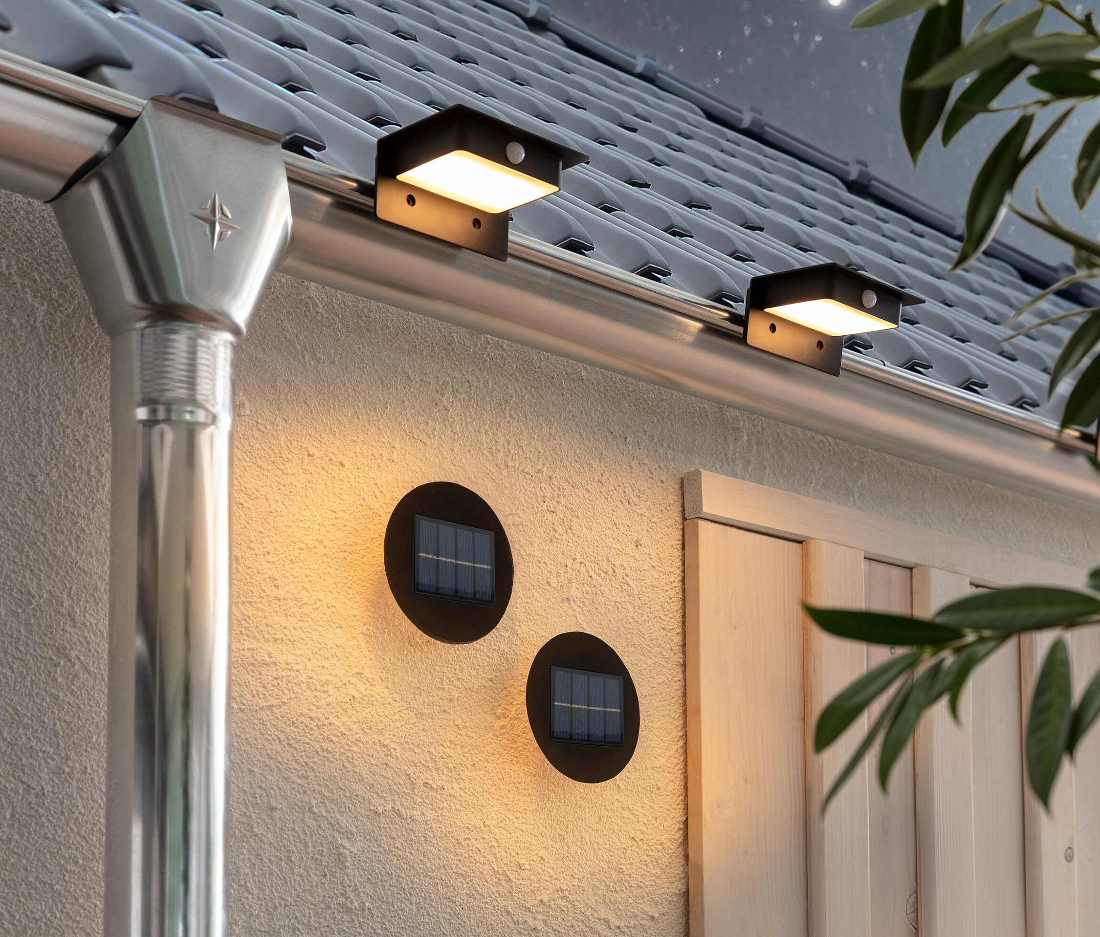 Deux lampes solaires murales et d’escalier Premium et trois lampes solaires pour gouttières sont fixées au mur et à la gouttière de la maison.