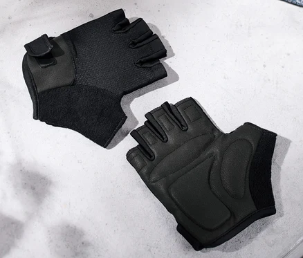 Deux gants de fitness noirs posés sur un banc gris à côté d'une serviette bleue.