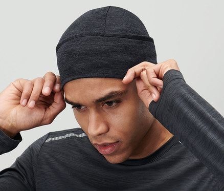 Un homme ajuste un bonnet en mérinos anthracite sur sa tête.