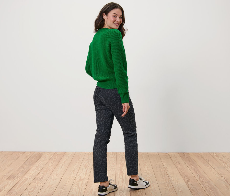 Une femme regarde par-dessus son épaule et porte un pull vert et un jean droit imprimé – Fit « Kira ».