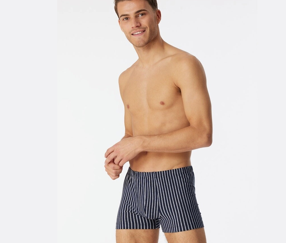 Un homme torse nu porte un short SCHIESSER en coton bio bleu foncé.