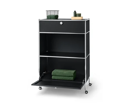 Commode métallique noire « CN3 » avec un tiroir sur lequel reposent un panier avec des serviettes et un compartiment à abattant sur lequel reposent deux serviettes.