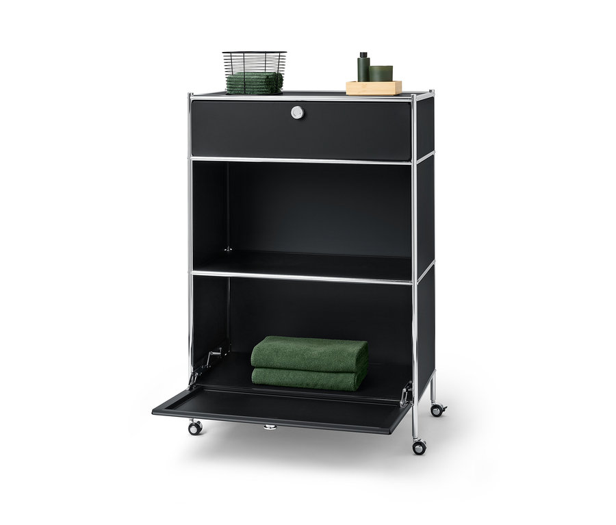 Commode métallique noire « CN3 » avec un tiroir sur lequel reposent un panier avec des serviettes et un compartiment à abattant sur lequel reposent deux serviettes.