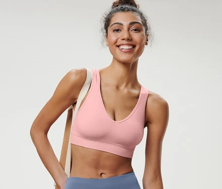 Une femme souriante portant une brassière de sport Seamless rose.