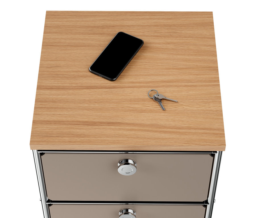 Sur le plateau en bois de la commode étroite en métal « CN3 » taupe à 2 tiroirs reposent un téléphone portable et des clés.