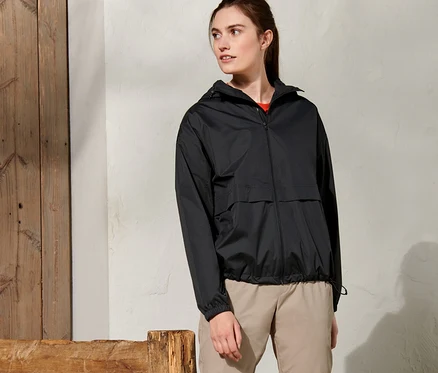 Femme debout à l'extérieur portant une veste de pluie noire.