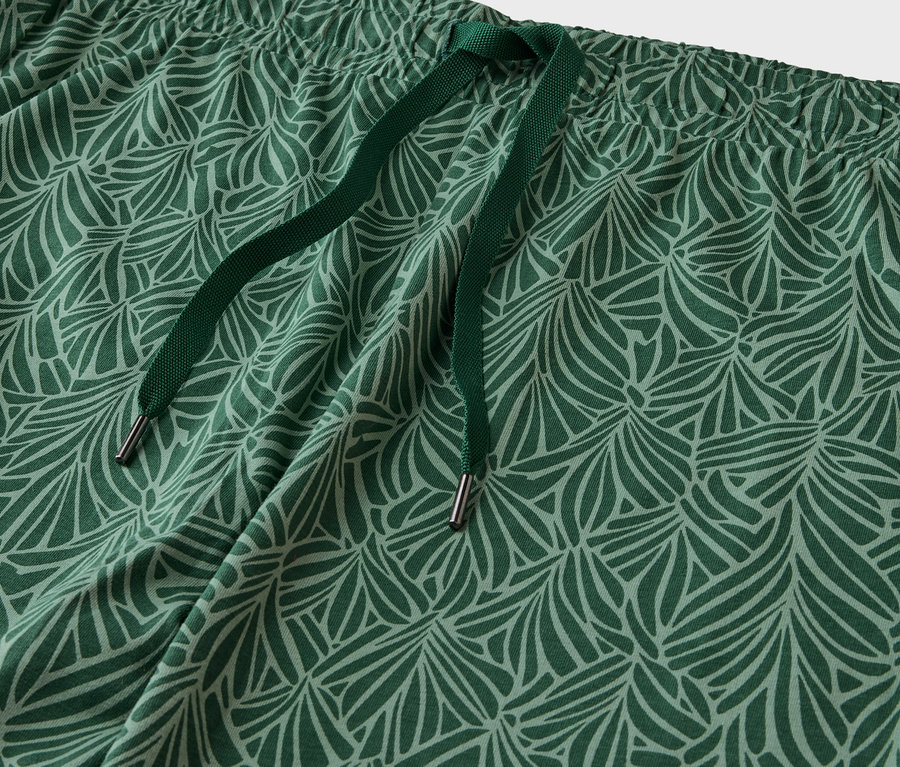 Détail d'un pantalon à motifs verts avec cordon de serrage.