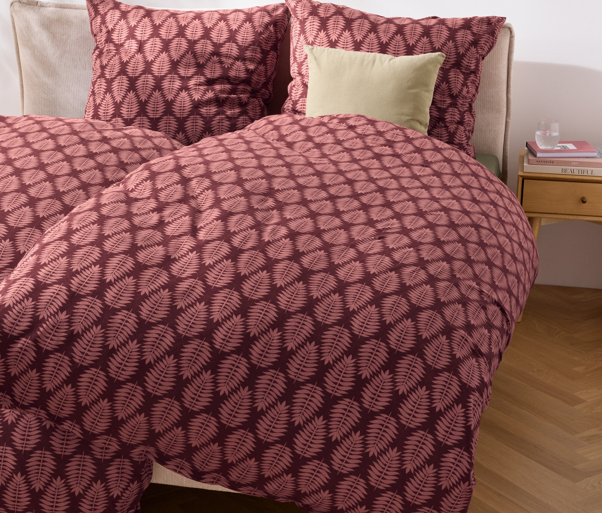 Gros plan d'un lit avec une parure de lit en jersey hivernal de taille normale et grande taille avec un motif de feuilles.