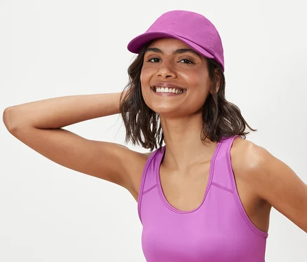 Femme posant en soutien-gorge de sport et casquette de sport.