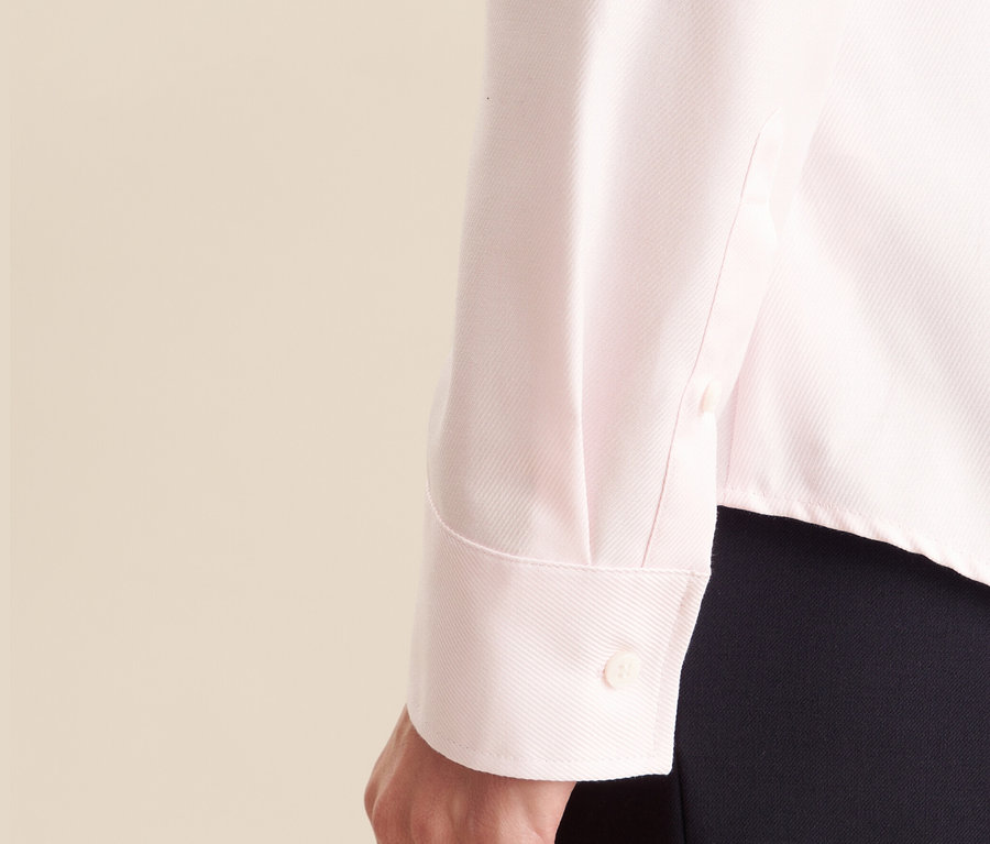 Gros plan sur la manche d'un chemisier en tulle rose de Seidensticker porté par une femme.