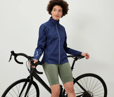 Une femme appuyée sur un vélo porte une veste cycliste 2 en 1.
