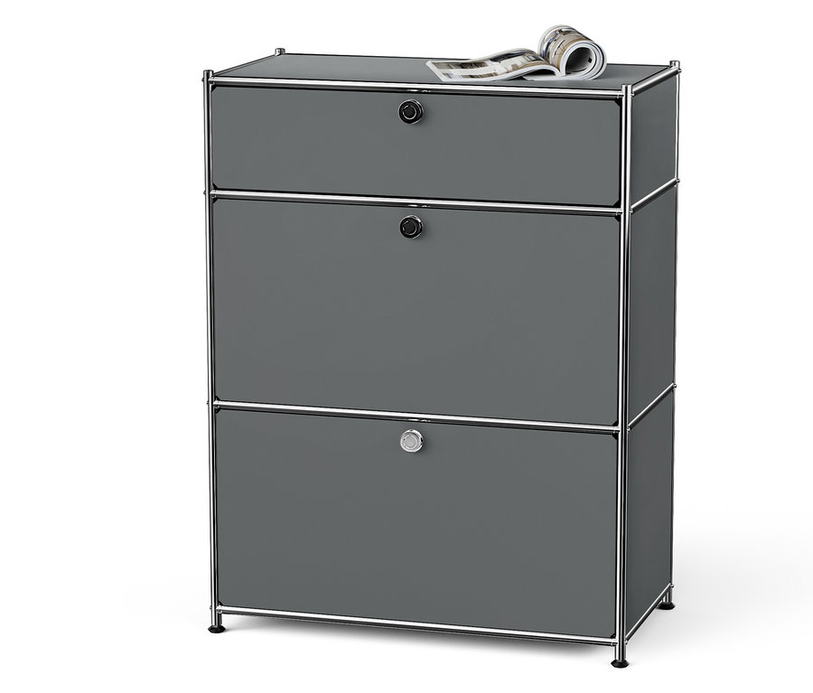 Commode grise à trois tiroirs avec cadre chromé et un magazine sur le dessus.
