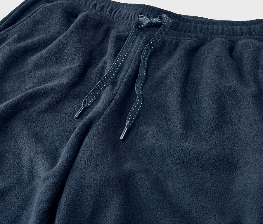Gros plan sur un pantalon de survêtement bleu marine avec cordon de serrage.
