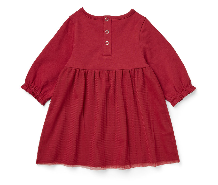 Détail d'une robe rouge à manches longues avec jupe en tulle.
