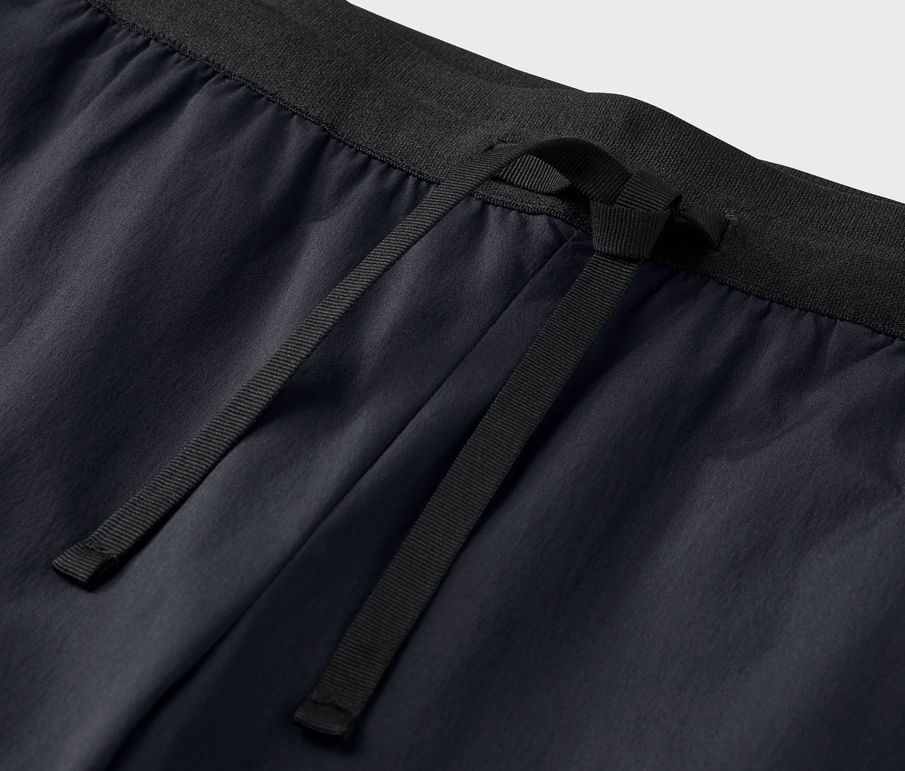 Gros plan sur un pantalon technique noir avec cordon de serrage.