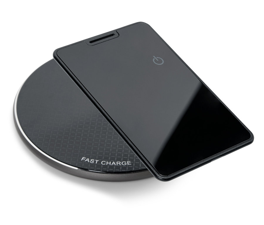 Un smartphone noir est posé sur un chargeur sans fil noir et rond.