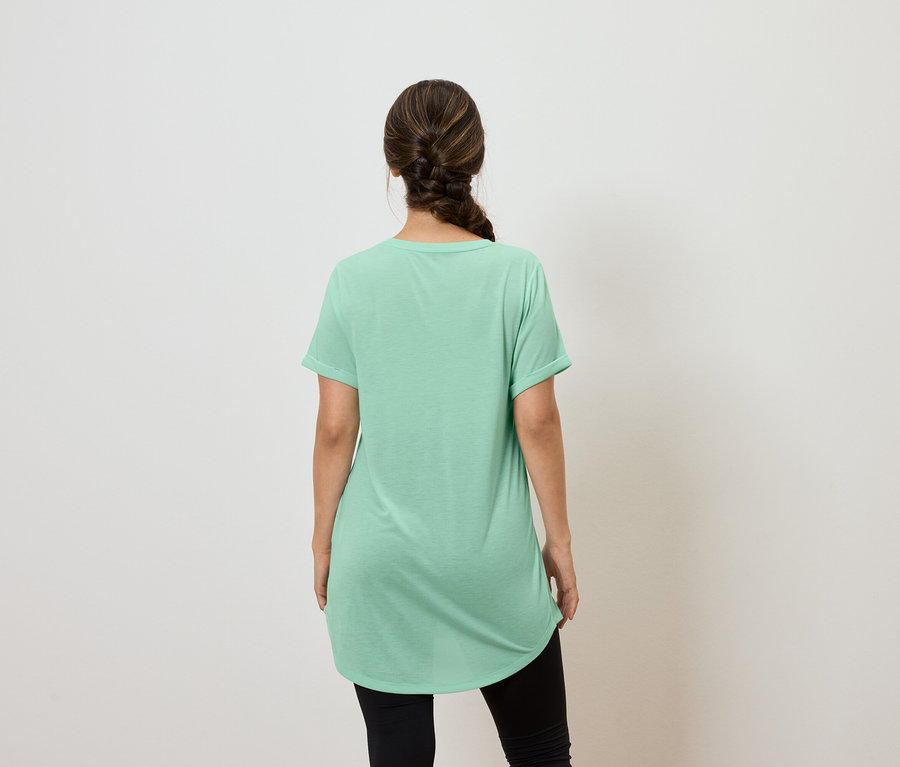 Une femme, vue de dos, porte un t-shirt vert et un legging noir.