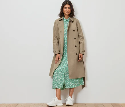 Femme debout portant un trench-coat, sable.