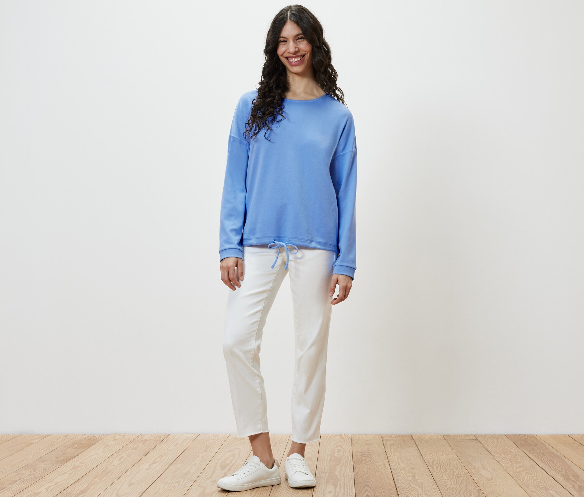 Une femme debout portant un sweat-shirt bleu clair.