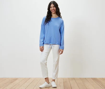 Une femme debout portant un sweat-shirt bleu clair.