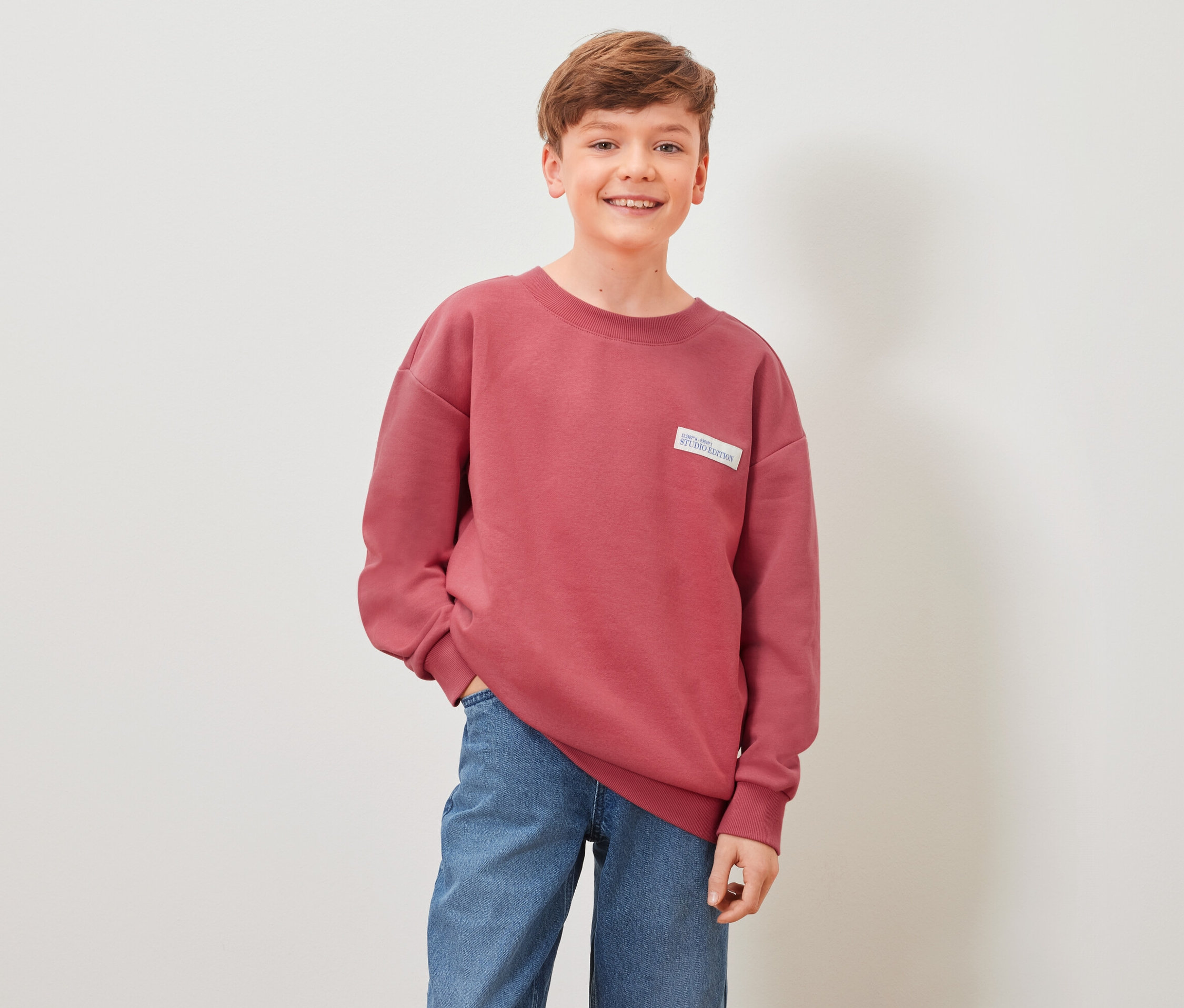 Garçon posant en sweat-shirt rouge pour enfant.
