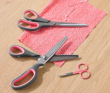 Un jeu de ciseaux à tissu repose sur un morceau de tissu à motifs floraux.