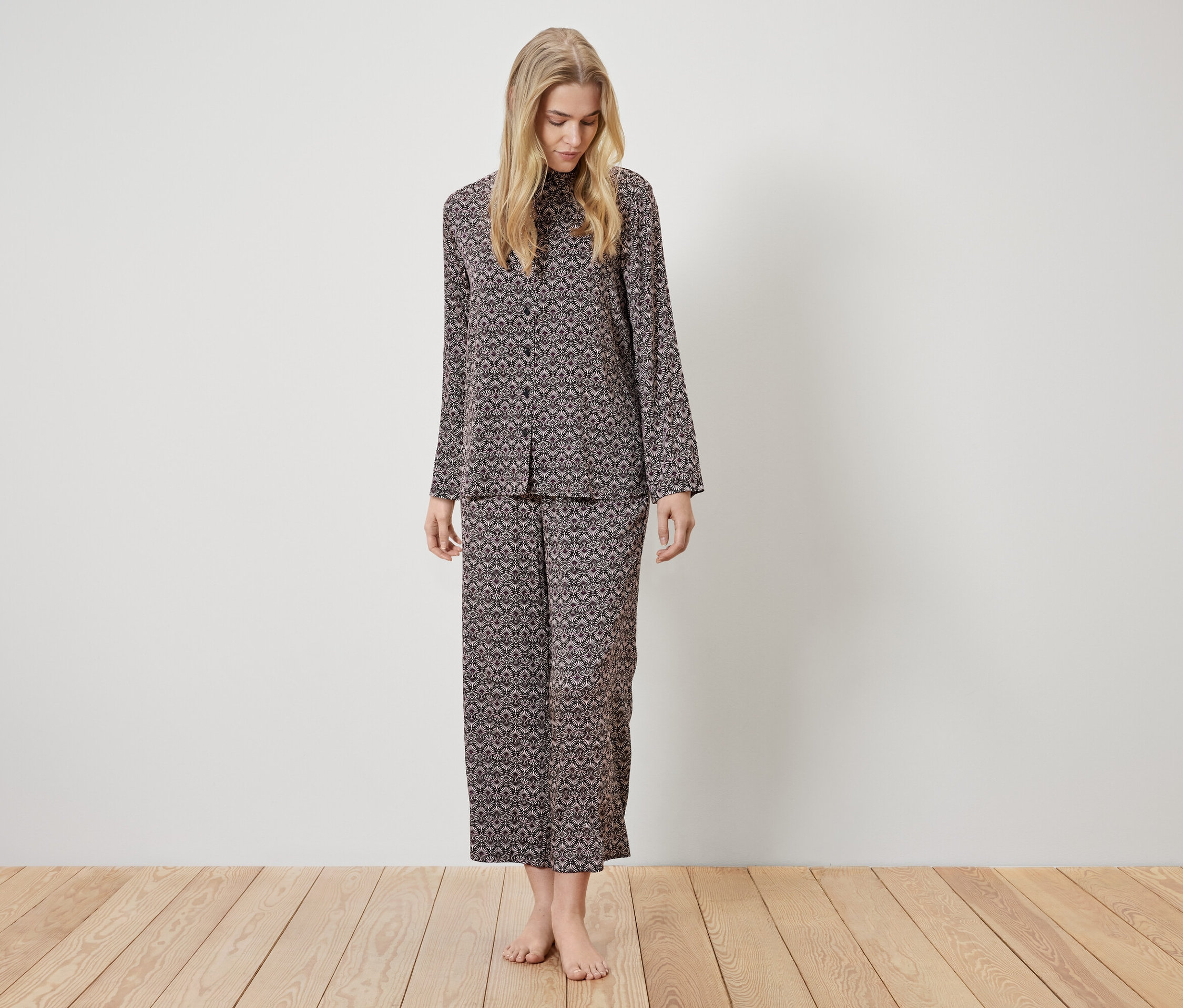 Une femme debout porte un pyjama marron à motifs.