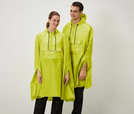 Une femme et un homme souriants posent en ponchos jaunes à capuche.