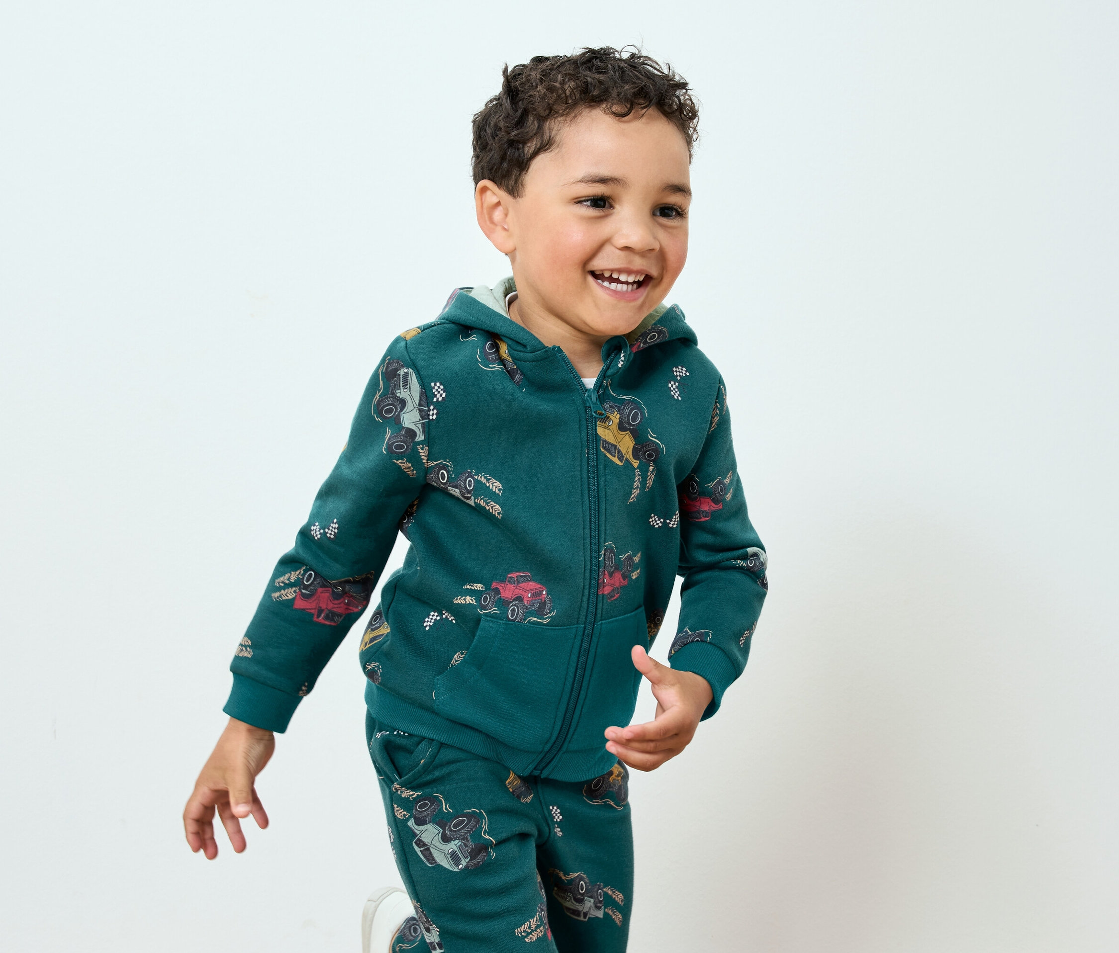 Garçon souriant en survêtement vert avec imprimé de voitures