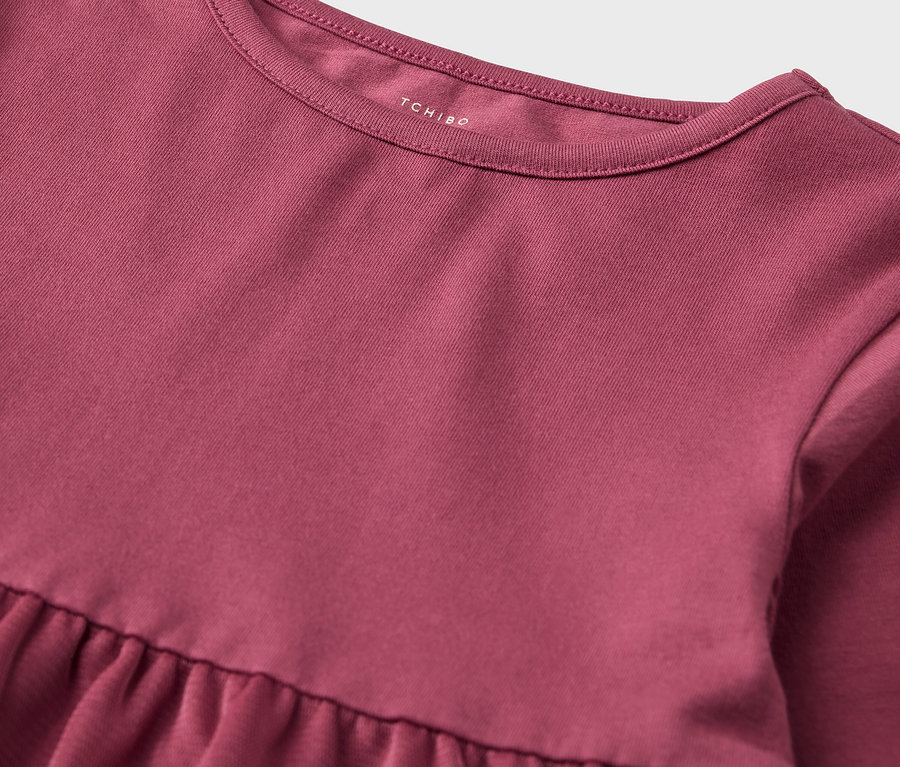 Gros plan d'une robe rose avec une jupe à volants et une encolure arrondie.