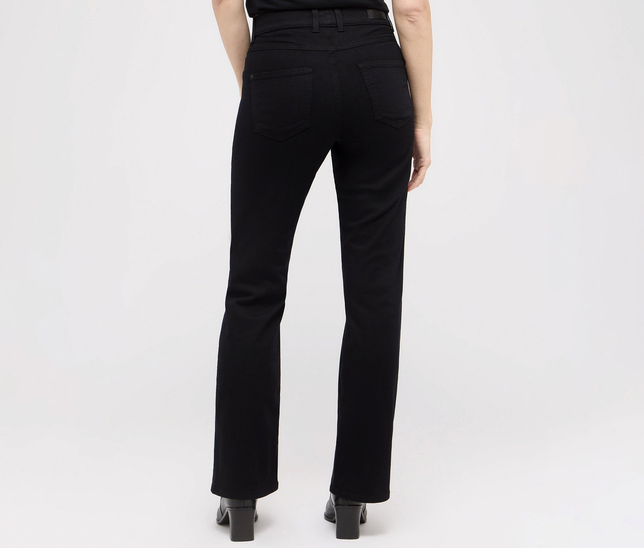 Vue arrière d'une femme portant un jean noir Angels Denim «	Lara	», coupe droite, et des chaussures à talons hauts.