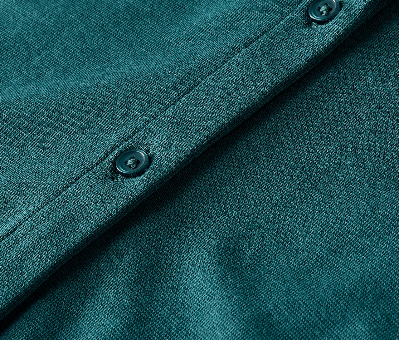 Gros plan sur un cardigan en tricot vert avec des boutons.