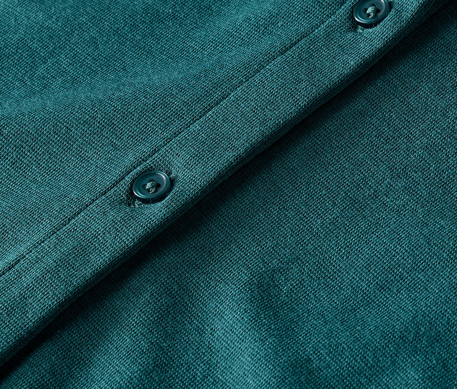 Gros plan sur un cardigan en tricot vert avec des boutons.
