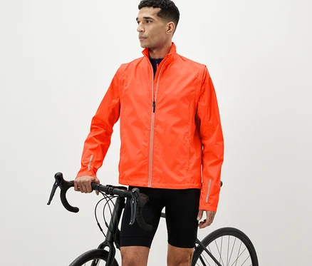 Un homme se tient à côté d'un vélo et porte une veste de cycliste orange 2 en 1.