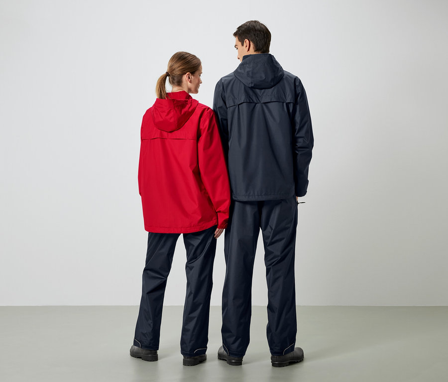 Deux personnes vues de dos portant des vestes de pluie et des pantalons de pluie. La femme porte une veste rouge et l'homme une veste bleu foncé.