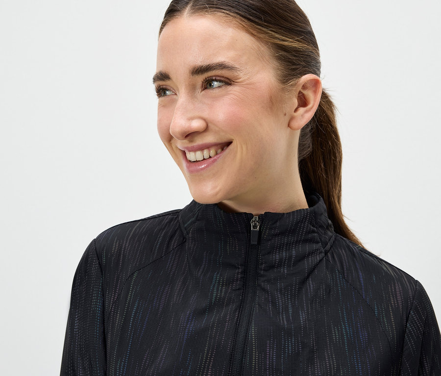 Portrait d'une femme souriante portant une veste noire zippée.