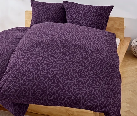 Linge de lit à fleurs violettes sur un lit.