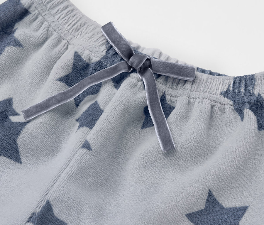 Détail d'un pantalon gris à étoiles avec un nœud.