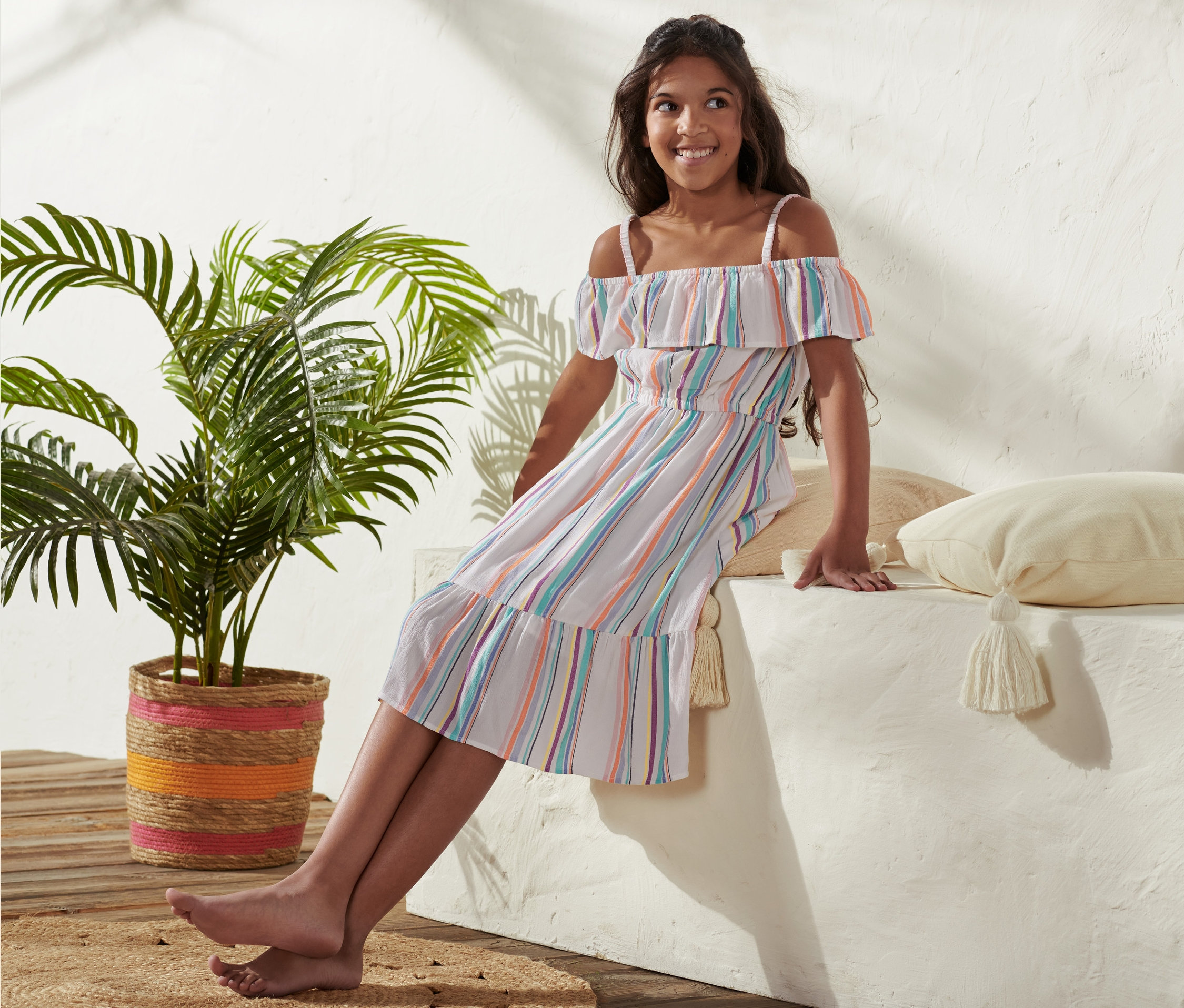 Une fille est assise sur un muret et porte une robe tissée en viscose.