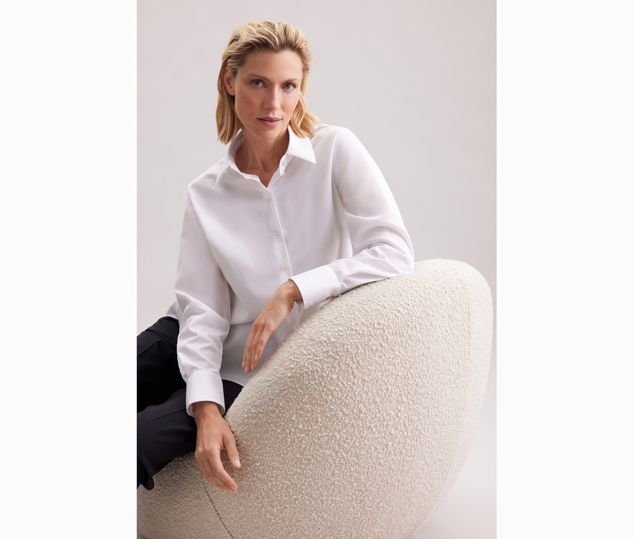 Femme assise sur un fauteuil portant une blouse-chemise blanche grande taille Seidensticker.