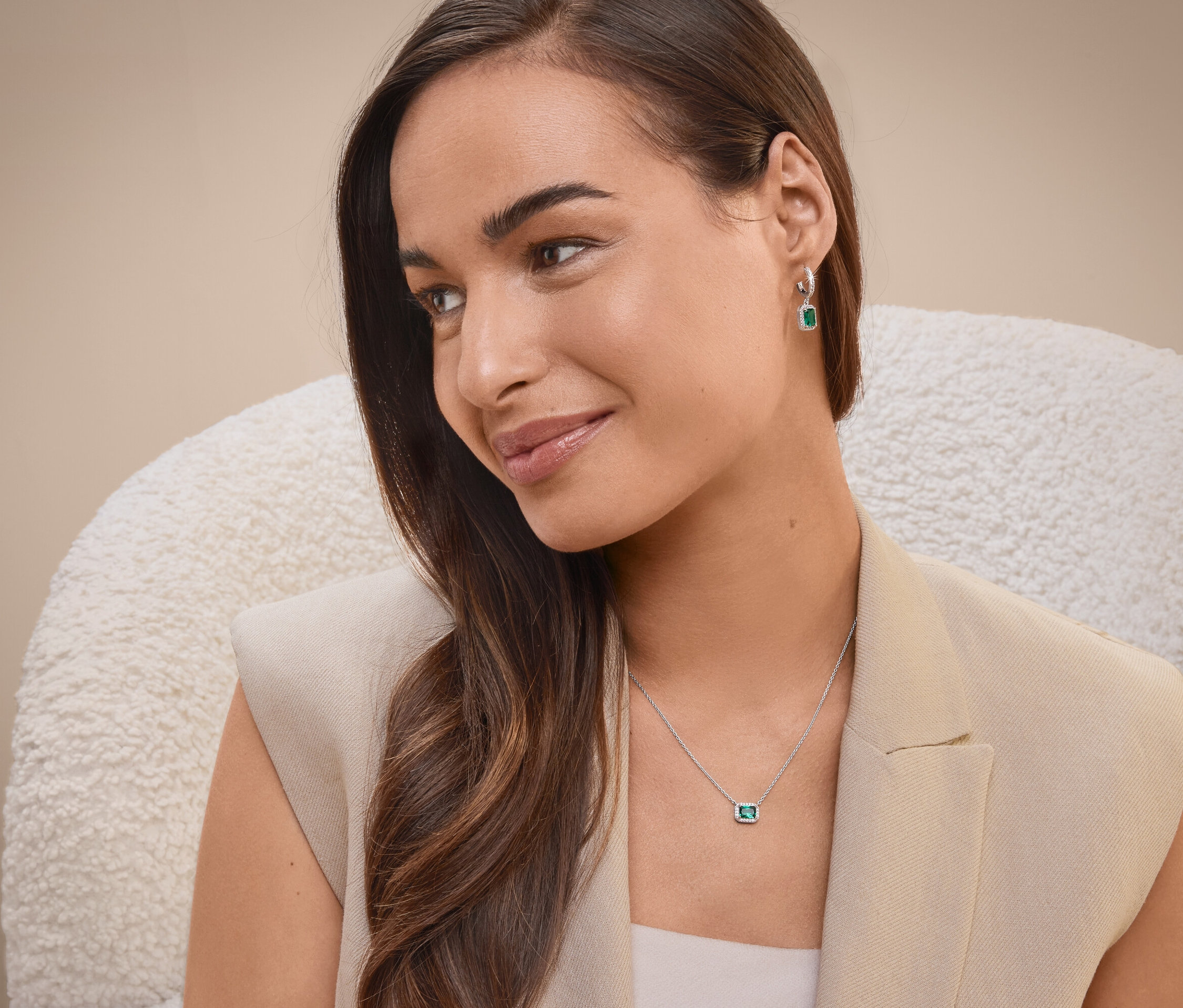 Une femme assise sur une chaise portant un collier et des boucles d'oreilles.
