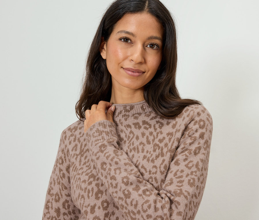 Une femme aux longs cheveux foncés porte un pull marron clair à motif léopard.