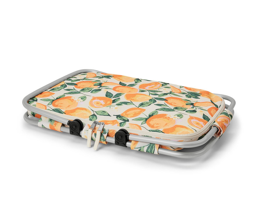 Un panier isotherme plié avec un motif d'oranges et une fermeture éclair blanche sur un fond blanc.